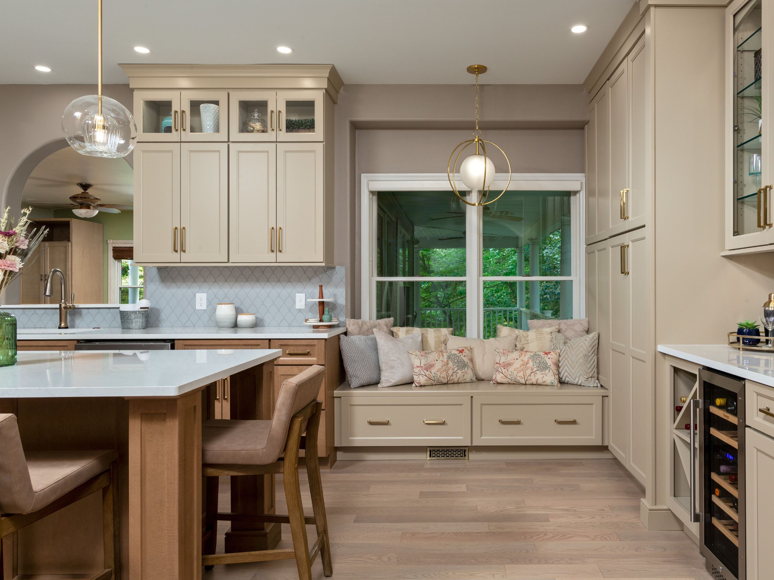 Custom kitchen window bench with storage drawers, cream cabinetry, and built-in beverage center.